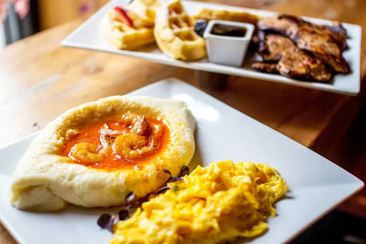 Shrimp and parmesan grits with scrambled eggs. Waffes with rum-spiced whipped cream